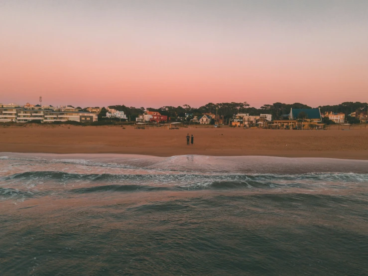 a man is walking on the beach in a distance with a kite