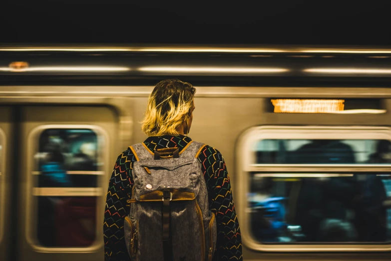 a person with a back pack standing near a train