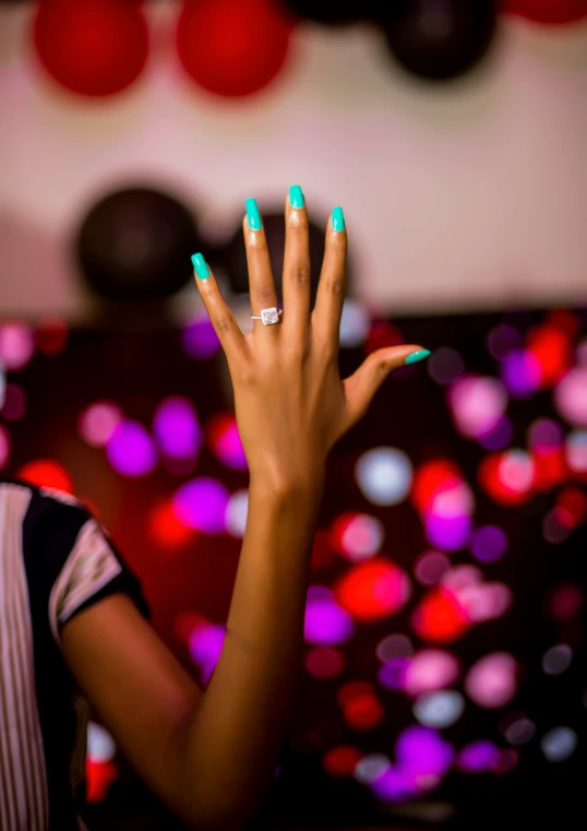 a woman with a manicured hand holding up two rings