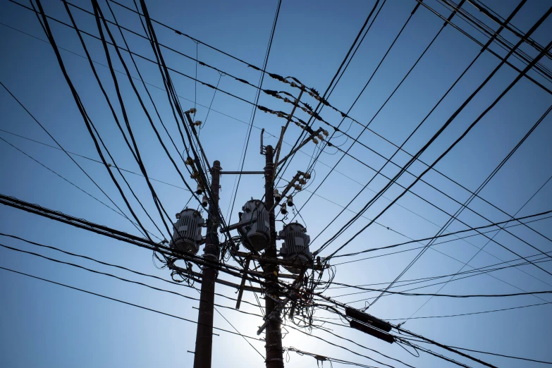 wires, electrical posts and telephone poles silhouetted against the blue sky