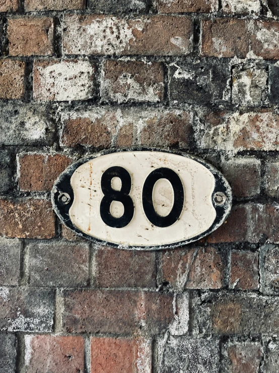 a brick wall has an old fashioned address sign