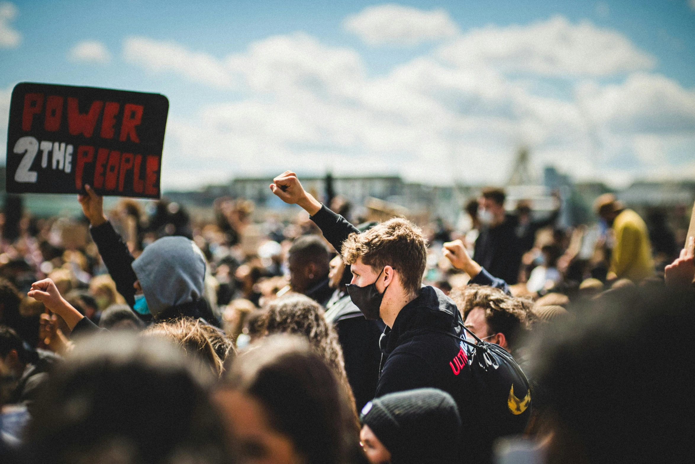 a young man is holding up a sign in front of a crowd