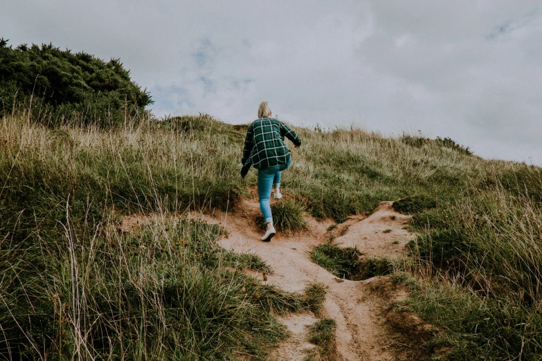 a person walking down a hill wearing blue jeans