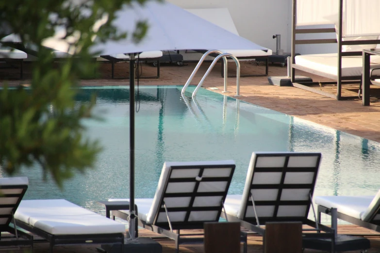 a long swimming pool with empty lounge chairs