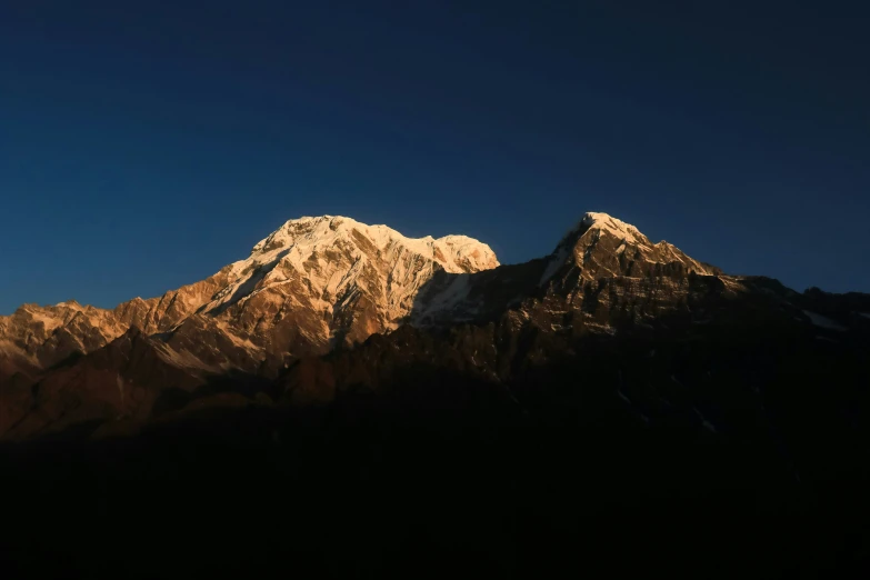 the snow - capped mountains are silhouetted against a blue sky