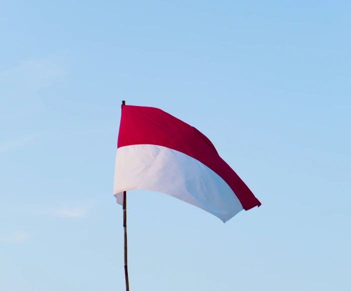 a small red and white flag is waving in the wind