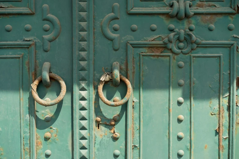 a close up image of a painted green door with two metal rings