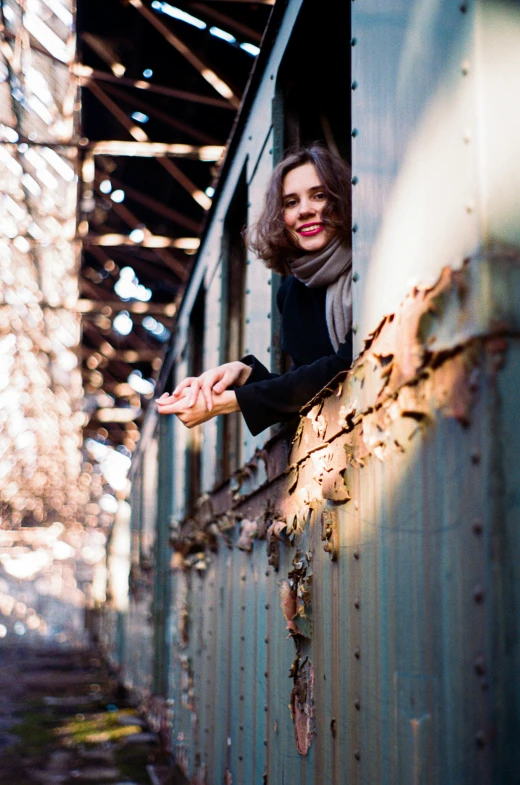 woman leaning out of train with arms outstretched looking outside