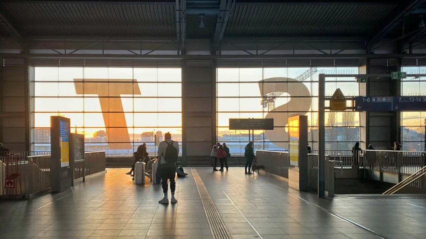 people walking towards a big window with an airplane in the background