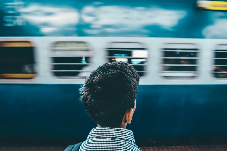 the back of a man's head standing next to a train