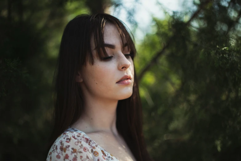 a girl with long hair stands outside and stares into the distance