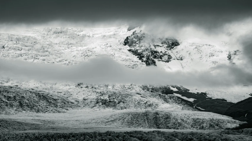 some snow covered hills and mountains under dark cloudy skies