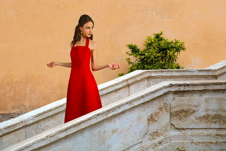 a woman in a red dress is on a ledge