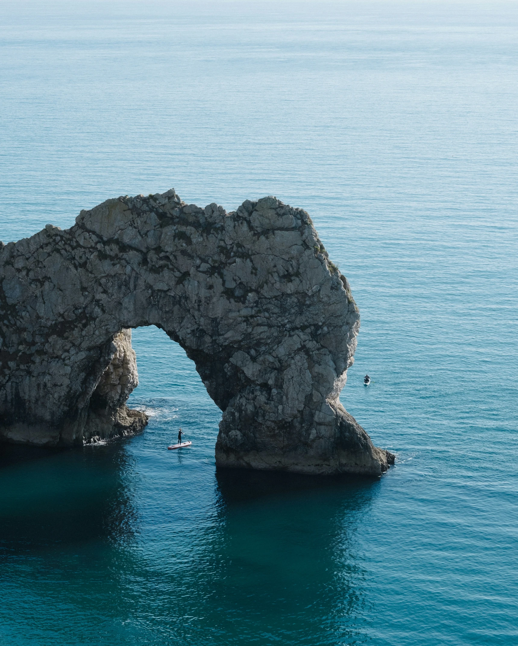 the rocky arch over the water is partially hidden by a rock