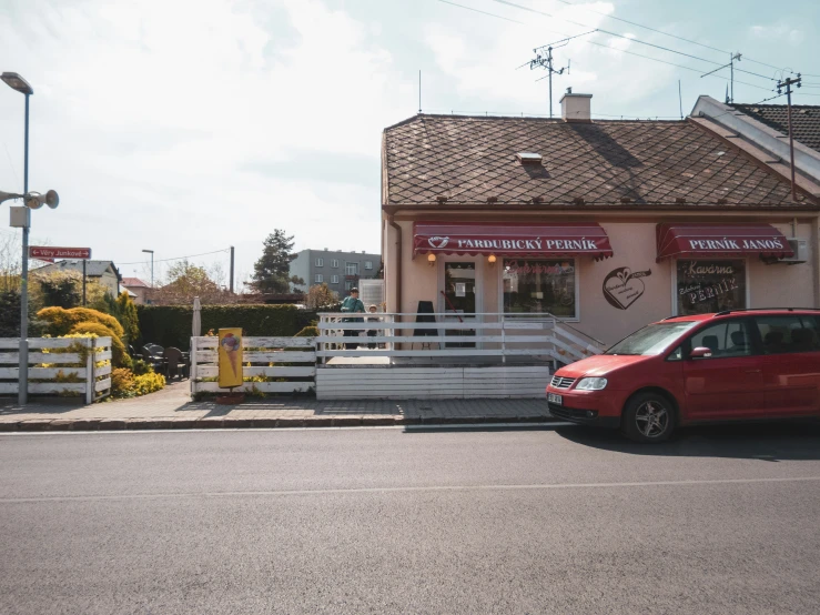 a red car parked outside of a small diner