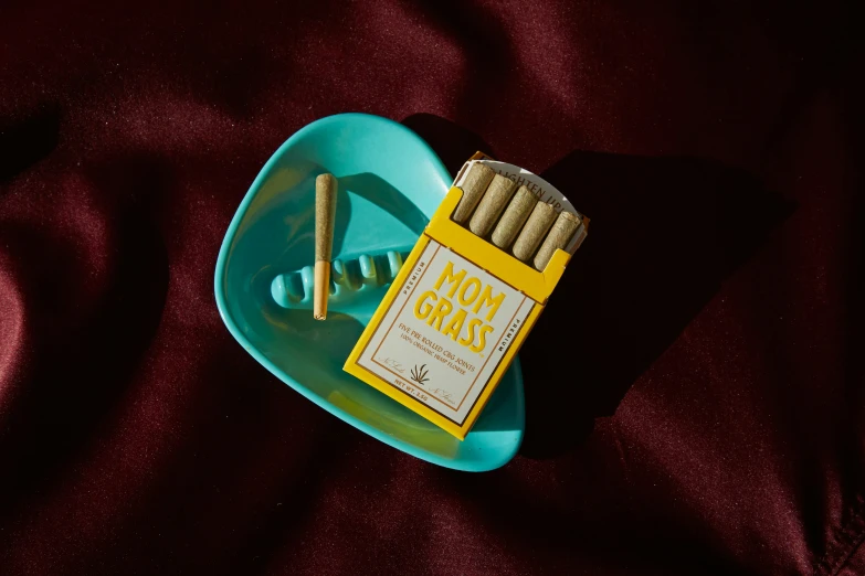 an empty yellow cigarettes pack and a match on a small blue tray