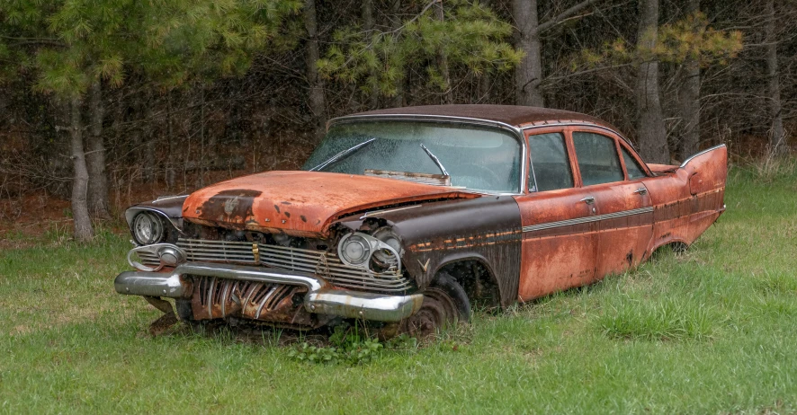 a rusty old car sits in a field