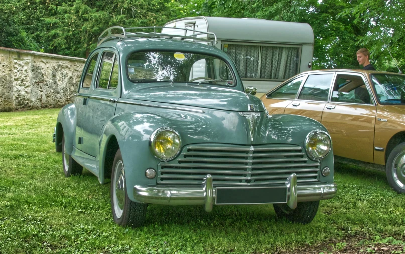 an old fashion car and truck sit parked in the grass