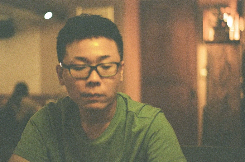 an asian man with glasses sitting at a table