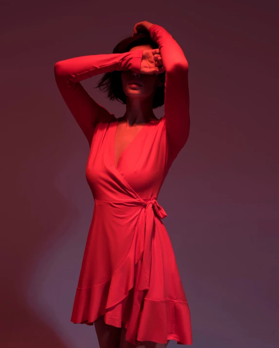 a woman in a red dress poses with her hand over her head