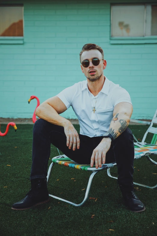 a man in white shirt and sunglasses sitting in chair