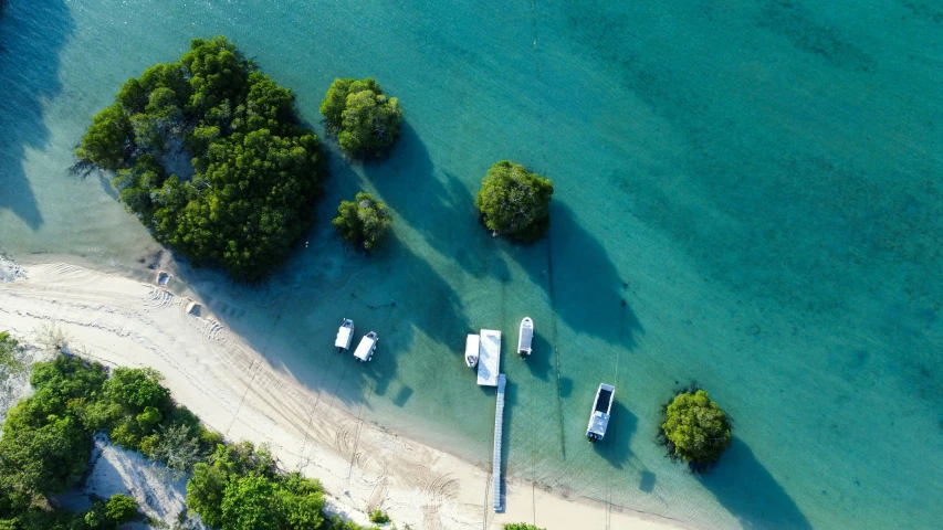 the aerial view shows several boats in a shallow blue river