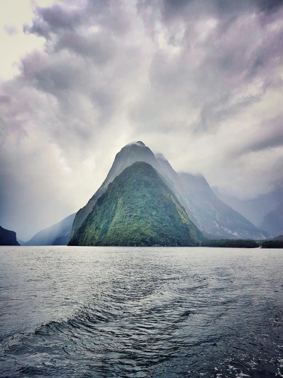 a boat in a body of water beneath a mountain