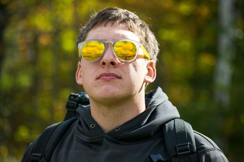 the man is wearing yellow sunglasses in the woods