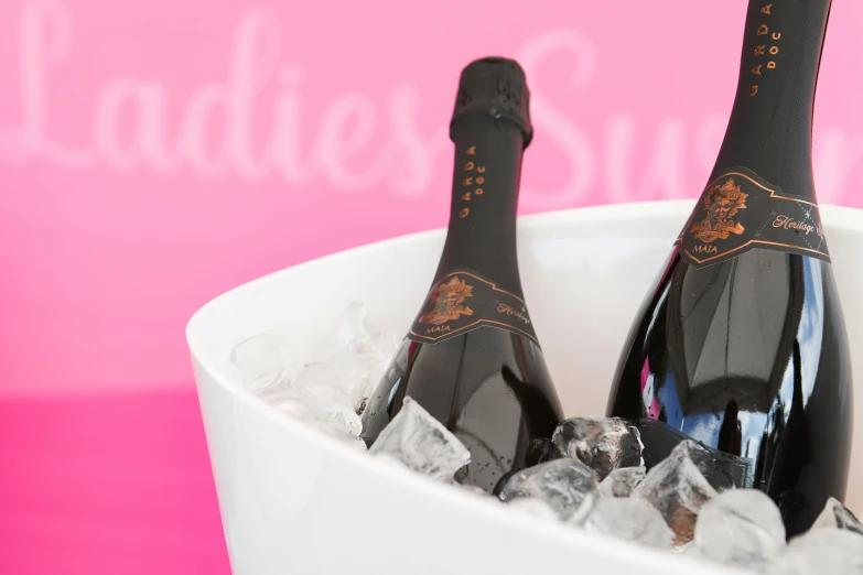 two bottles of champagne in ice on a pink table