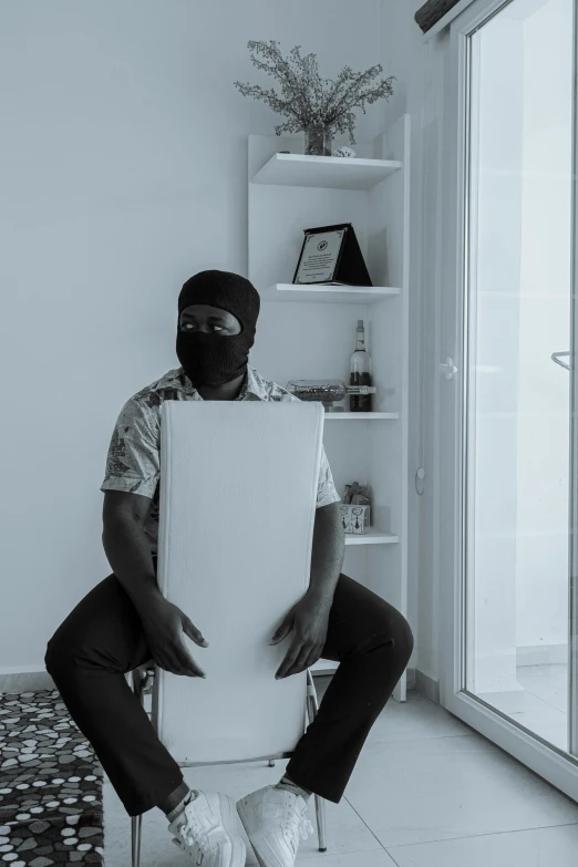a person in a mask sits on a toilet holding a cardboard box