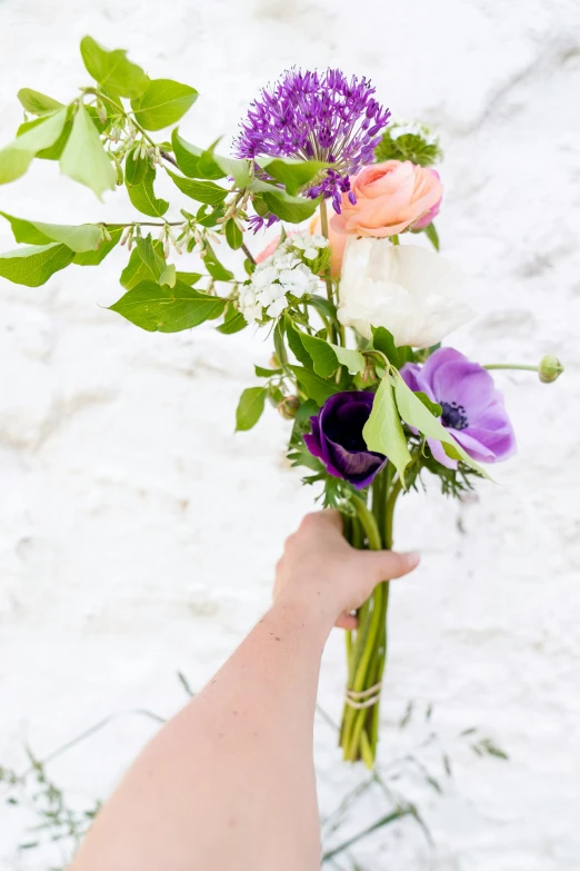 someone holding up the flowers from their bouquet in the snow