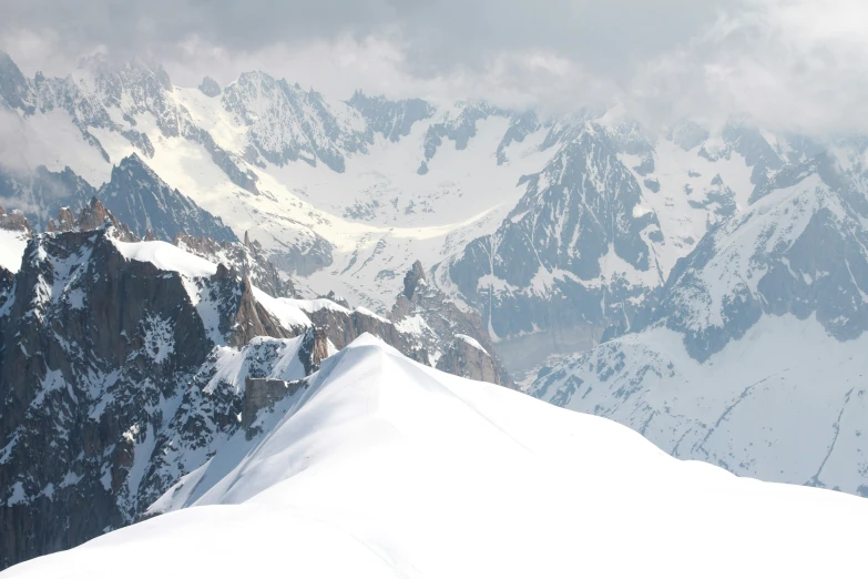 mountains are covered in snow and fog as someone stands on top