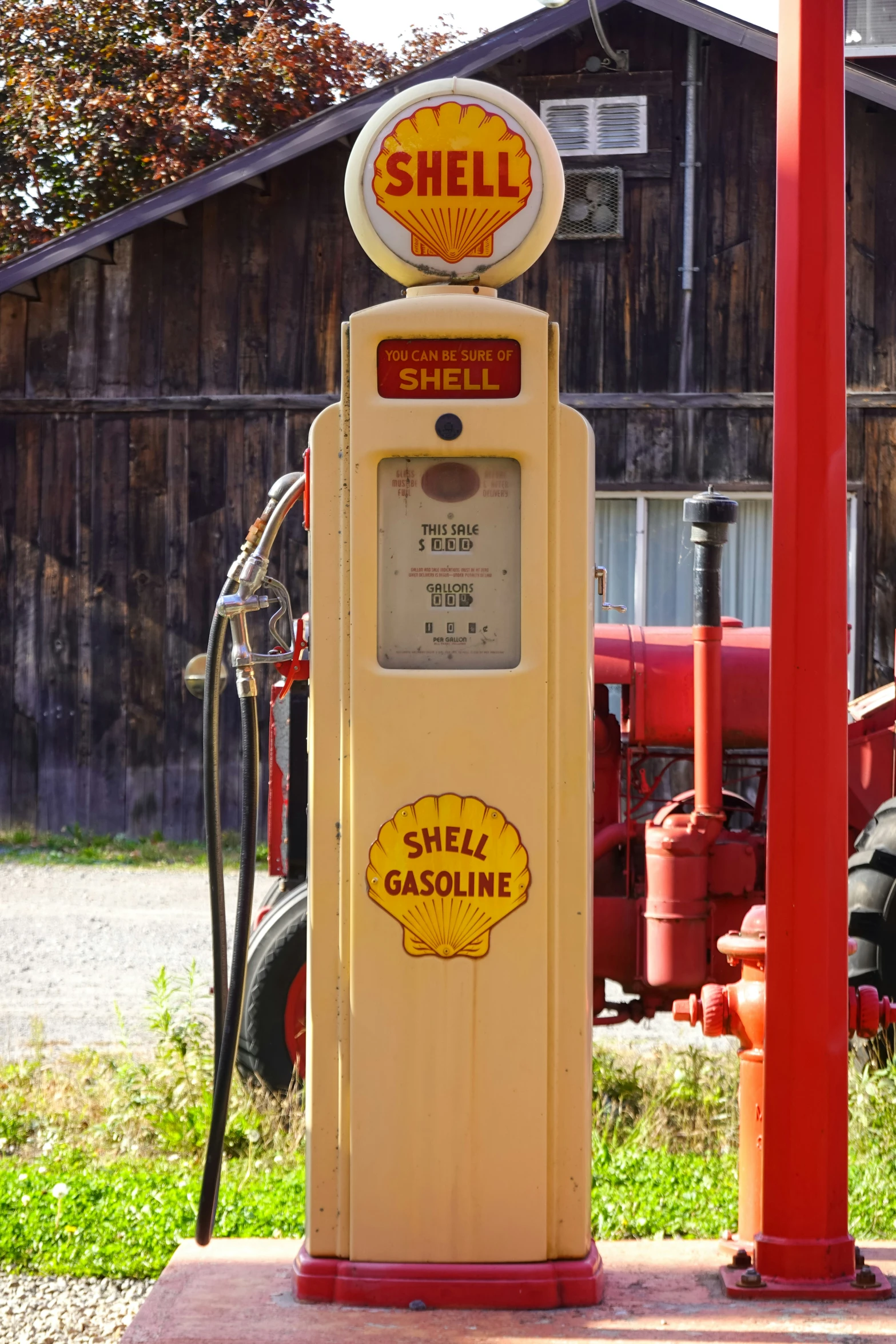 a yellow shell gas pump sitting outside a garage