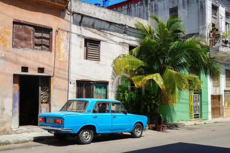 an old blue pickup truck is parked outside some buildings