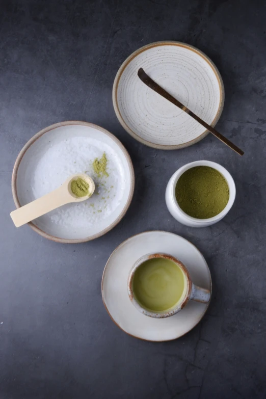 a tea cup next to two tea cups with green leaves