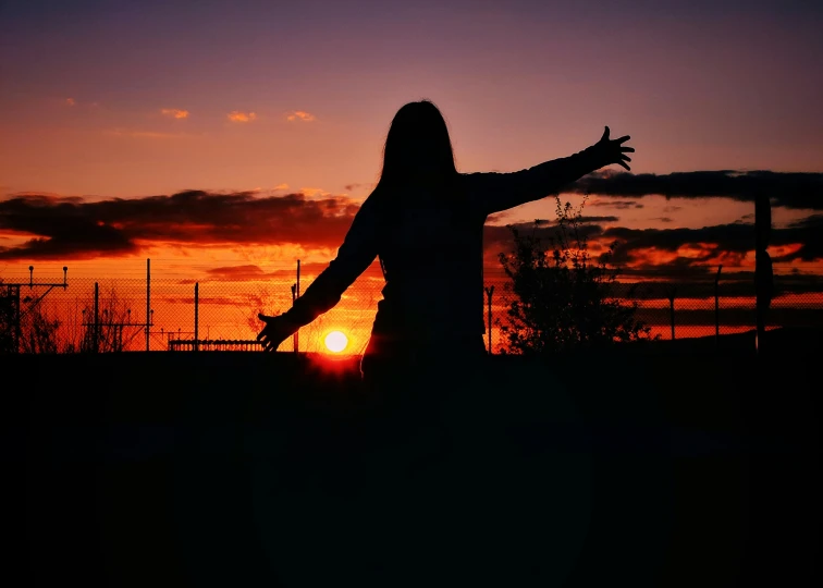 a person walking toward the sun with their arms outstretched