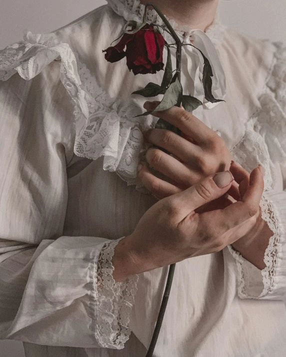 a woman wearing a white blouse holding a flower