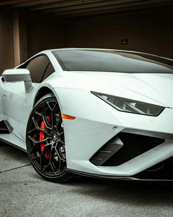 the front end of a white lambskin car parked in front of a garage door