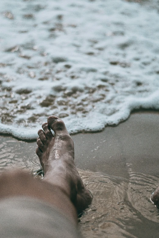 someone feet in water and ocean waves coming into shore