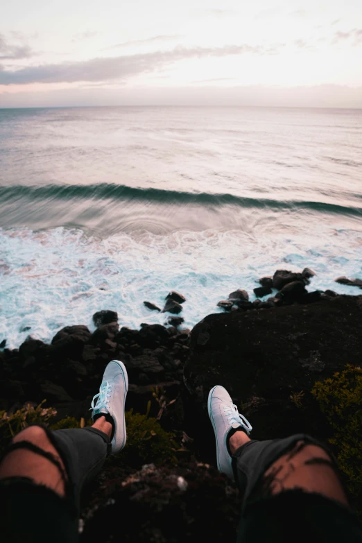 someone is standing on a rocky outcropping near the ocean