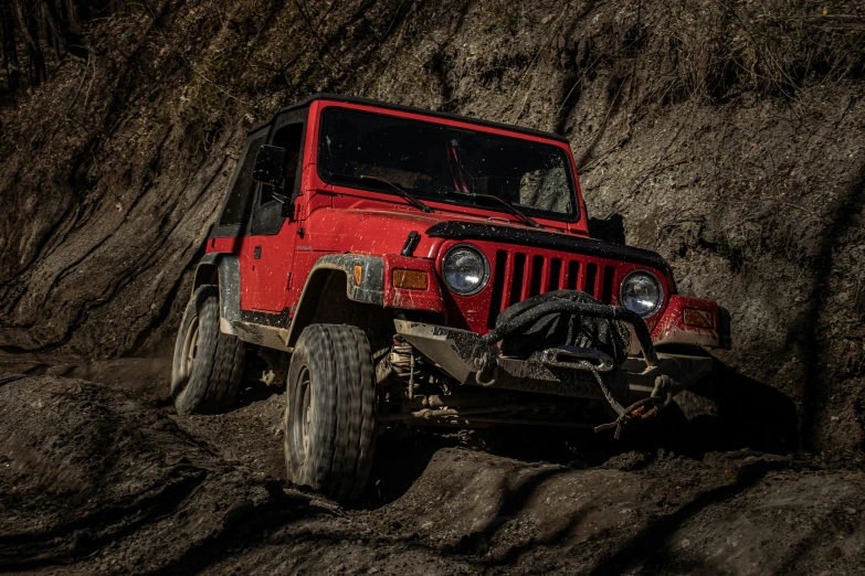 a red jeep is on a rocky road