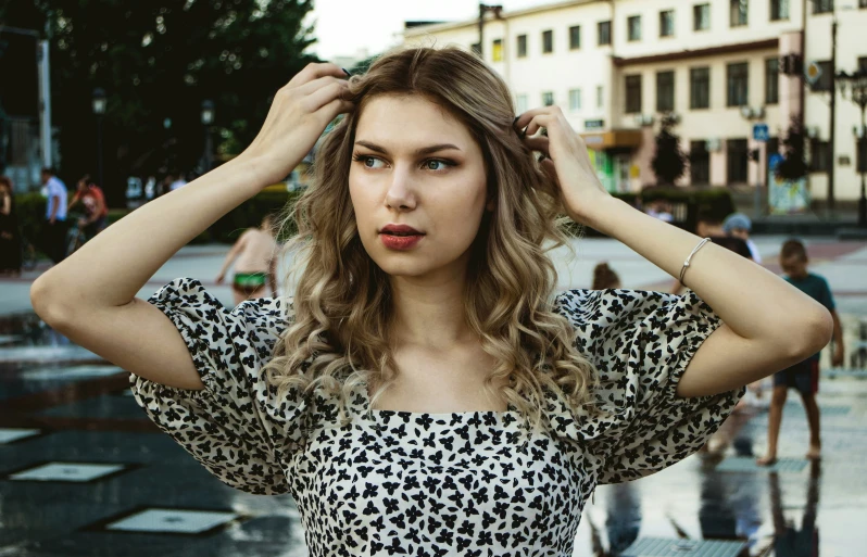 woman in a black and white shirt holding her head with both hands