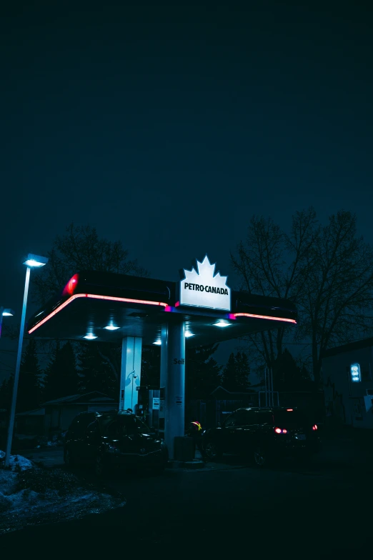 canadian gas station at night with cars parked in the street