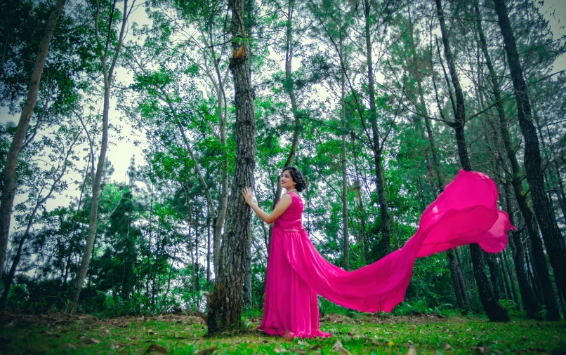 woman in red dress standing in the woods near trees