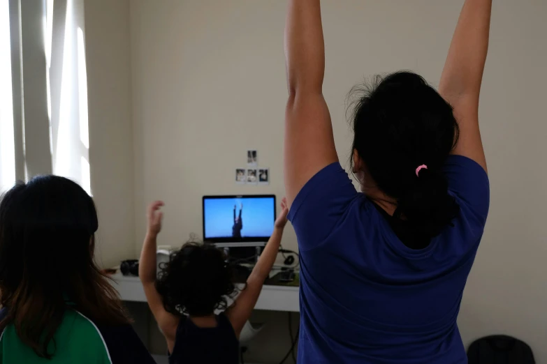 two women in a room with tv, one raising her arms in the air