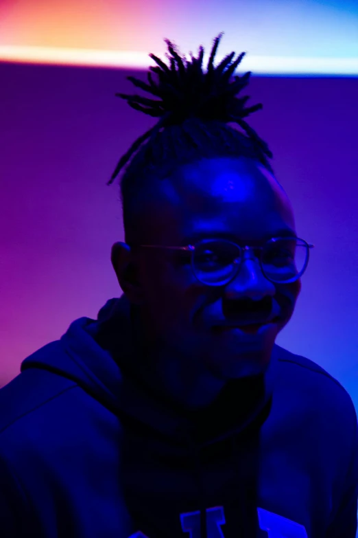 a man with glasses and dreadlocks poses for a picture