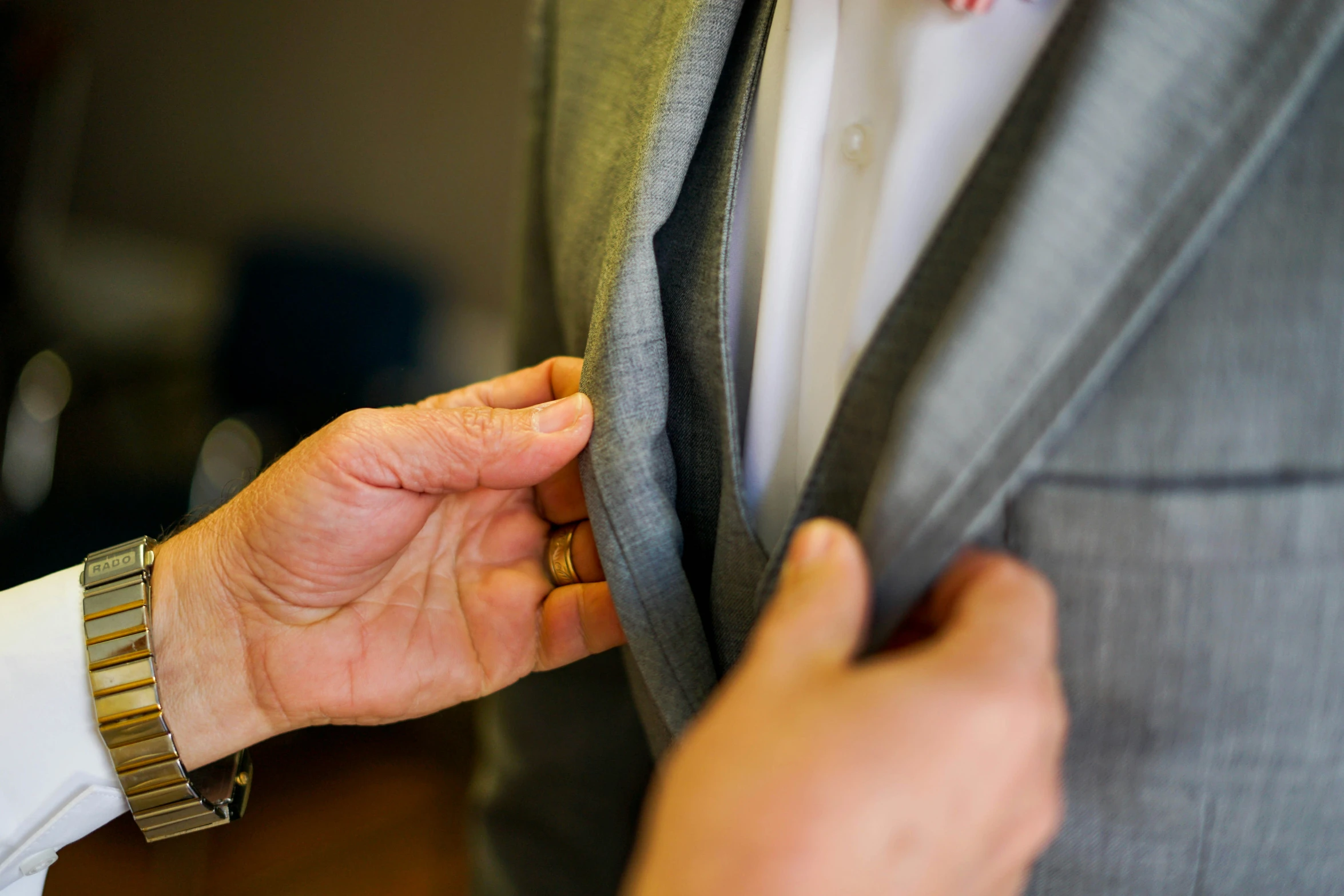 a man holding onto his suit jacket with a wedding ring