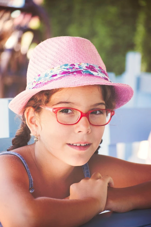 a small girl wearing pink hat and glasses