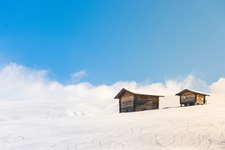 three small log cabins sitting on top of a snow covered slope