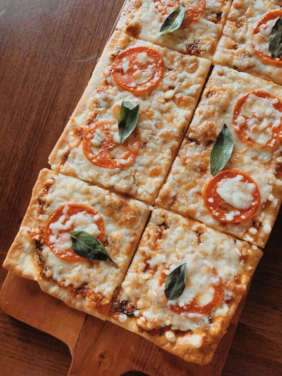 slices of pizza with tomato and basil on a wooden  board